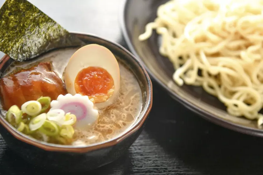 Primer plano de un plato de fideos y un plato de sopa de 拉面 con un huevo escalfado, 切.